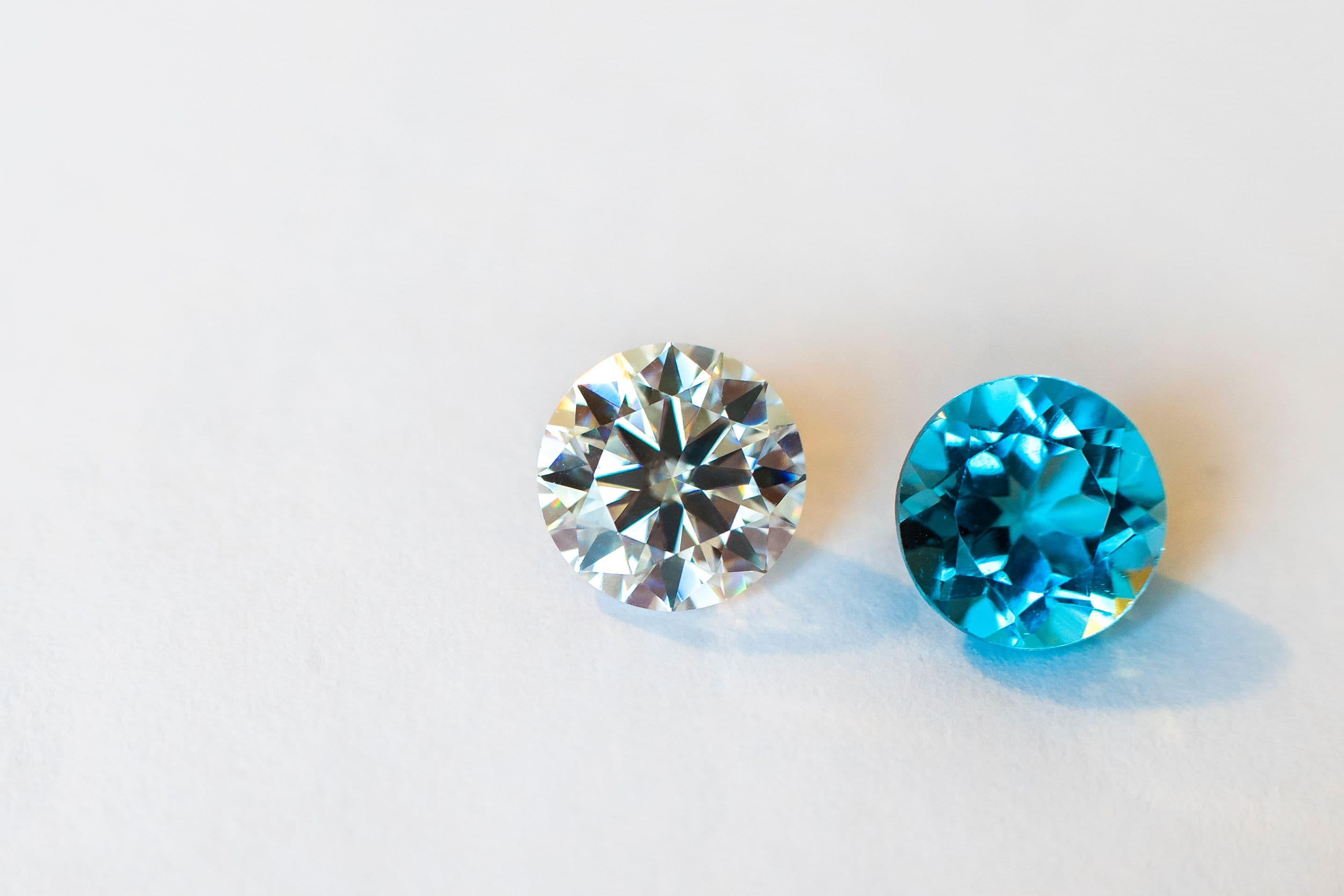 Close-up of a clear diamond and a blue gemstone side by side, illustrating hardness and durability differences among gemstones.